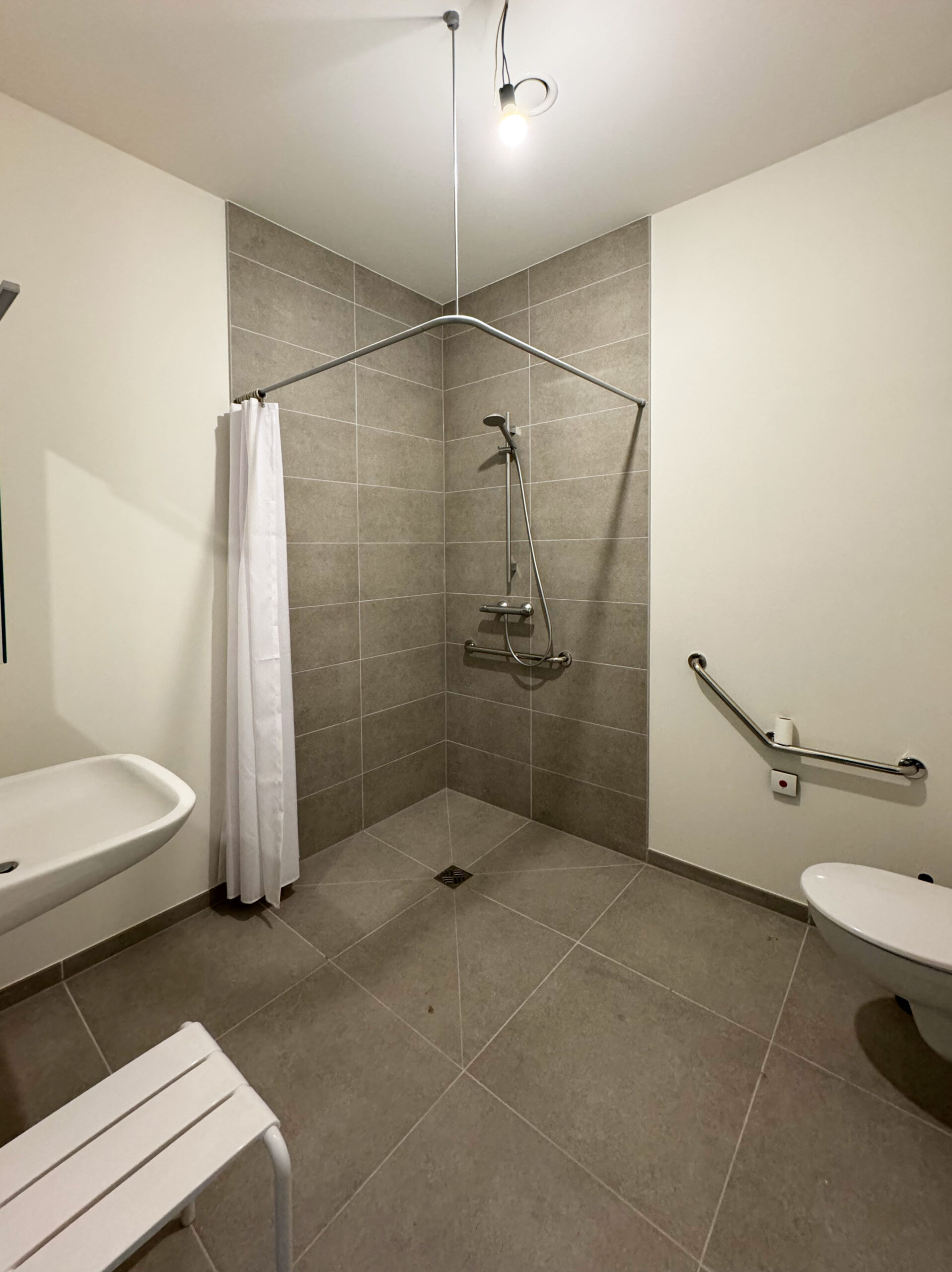 Toegankelijke badkamer in een assistentiewoning, uitgerust met een noodoproepsysteem voor extra veiligheid.